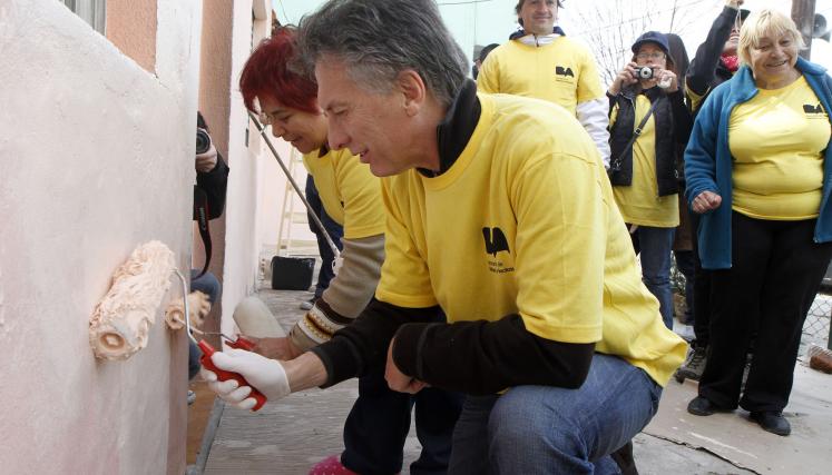 Macri plantó un árbol y pintó el frente de una casa, a cuya dueña le firmó una bandera de Boca Juniors, antes de recorrer el barrio junto al resto de los funcionarios. Foto: Mónica Martínez/GCBA. 