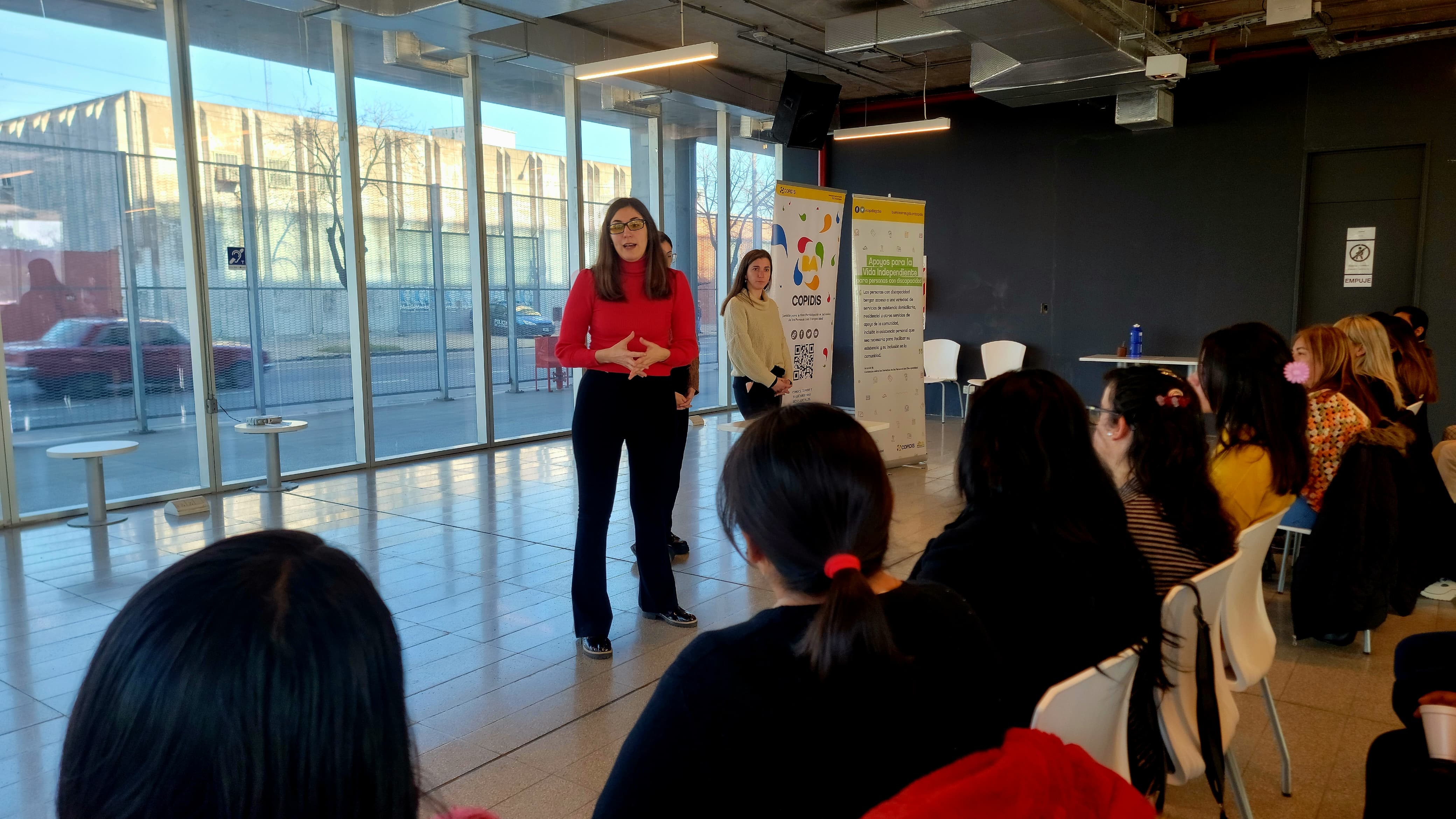 Mujer exponiendo su investigación de políticas ante un público atento y comprometido.