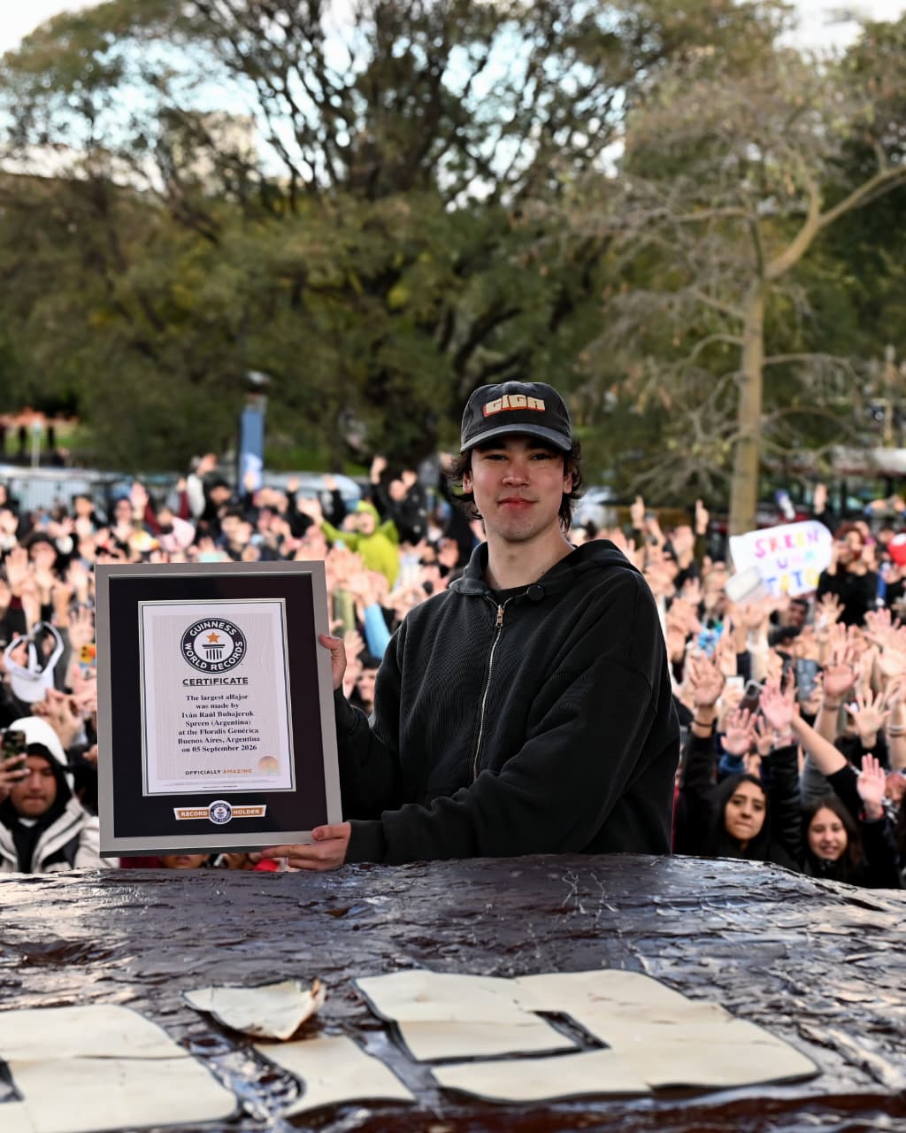 Spreen sostiene el certificado Guinness detrás del alfajor gigante