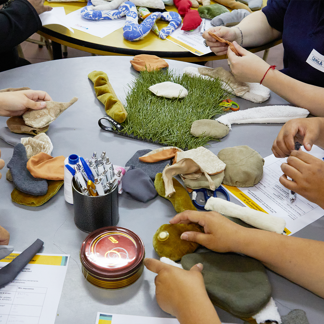 Participantes del taller creando juguetes sensoriales con telas, texturas y materiales reciclados.