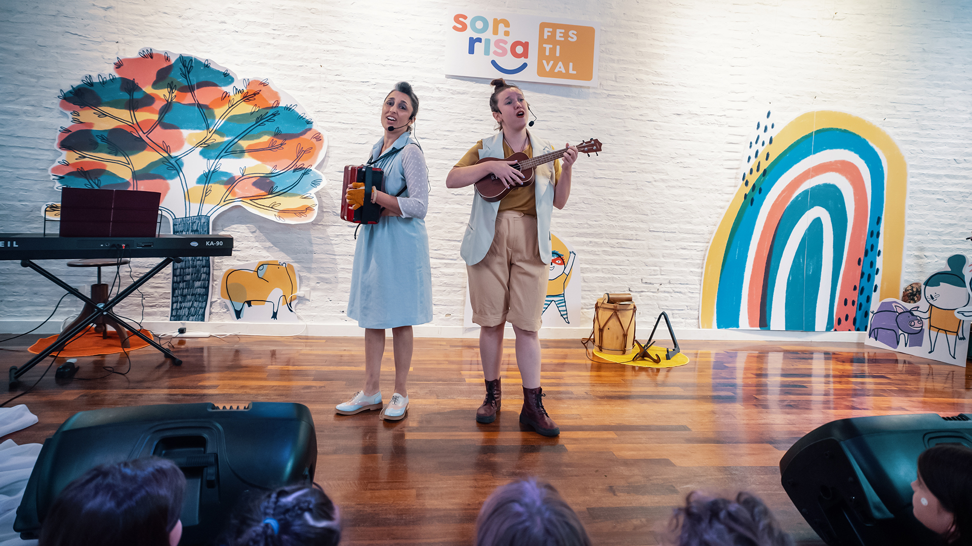 Duo Kalpataru tocando el ukelele y el acordeon frente a un publico de niños y niñas