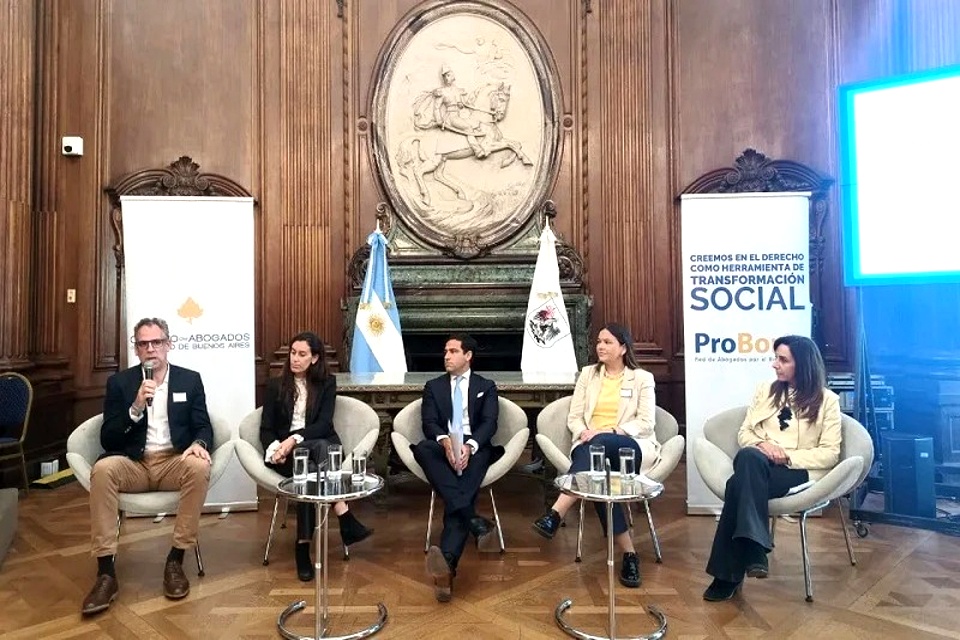 Panel de cinco personas participando en el lanzamiento del Protocolo en un salón de la Legislatura, con banderas y carteles oficiales de fondo.