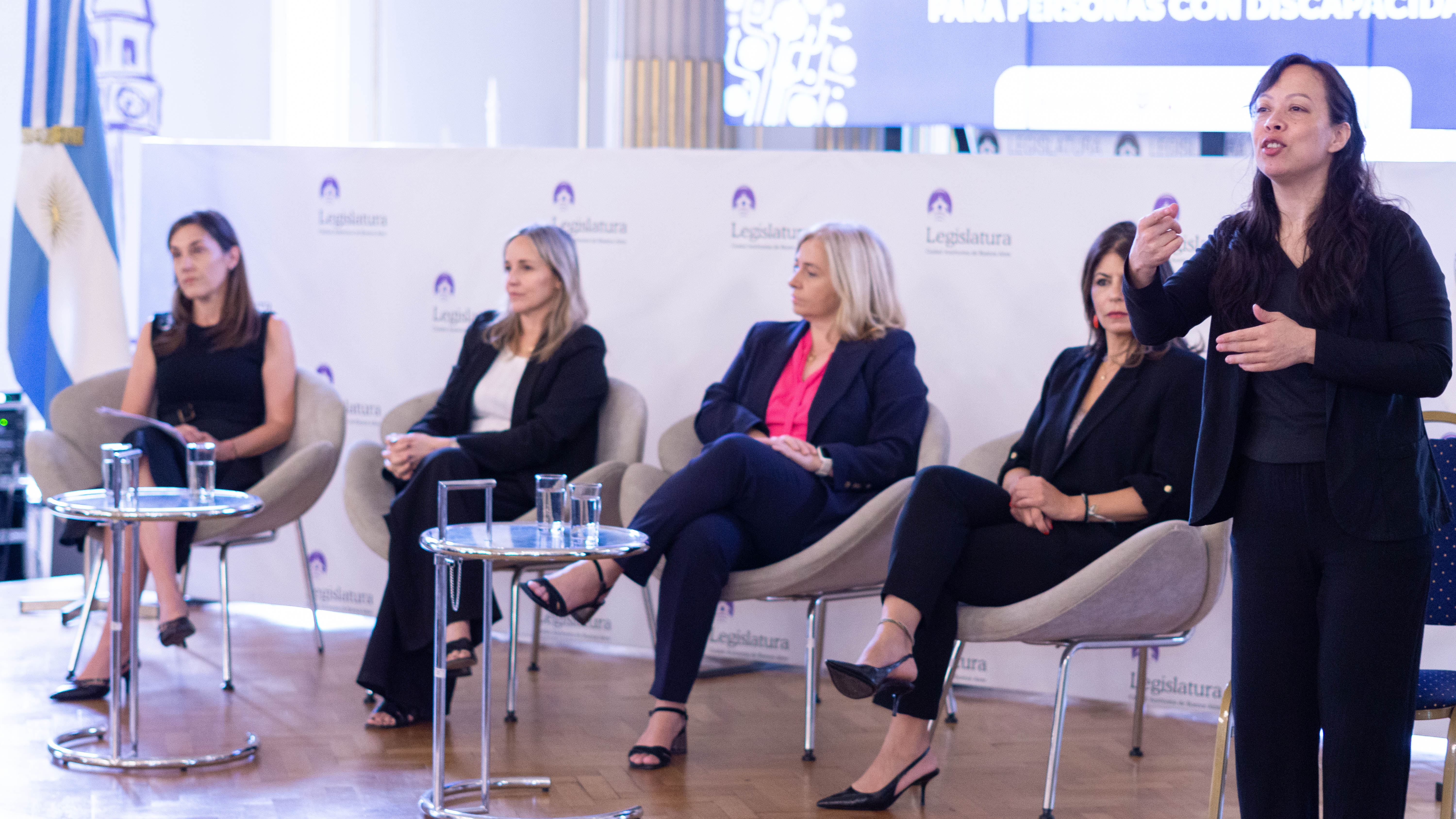 Panel de autoridades junto a una intérprete de LSA: Ana Ciuti, Clara Muzzio, Inmaculada Sanz y Luciana Binaghi sentadas en el escenario.