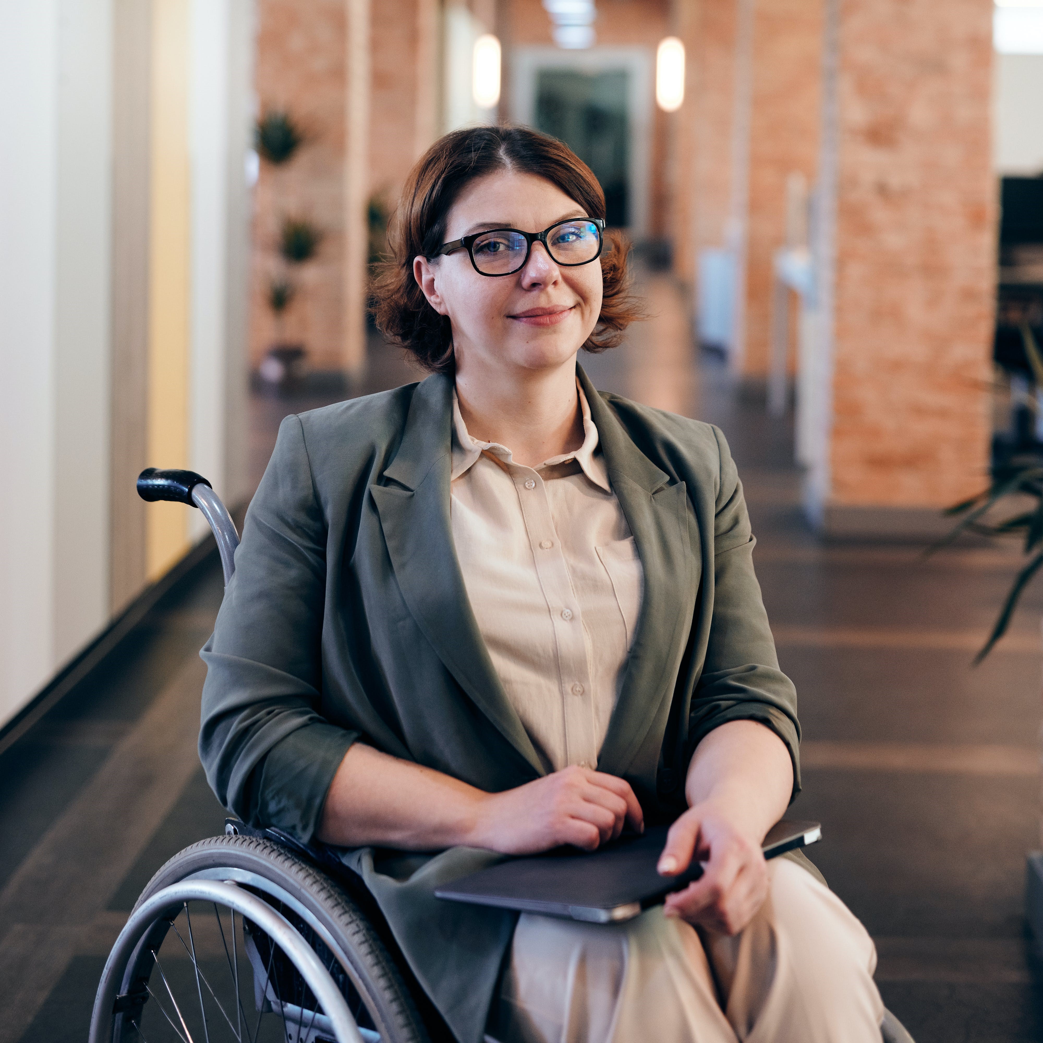 Fotografia de una mujer en silla de ruedas con notebook sobre las piernas en un ambiente laboral