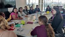 Varias personas reunidas alrededor de una mesa, conversando y compartiendo ideas en un ambiente colaborativo.