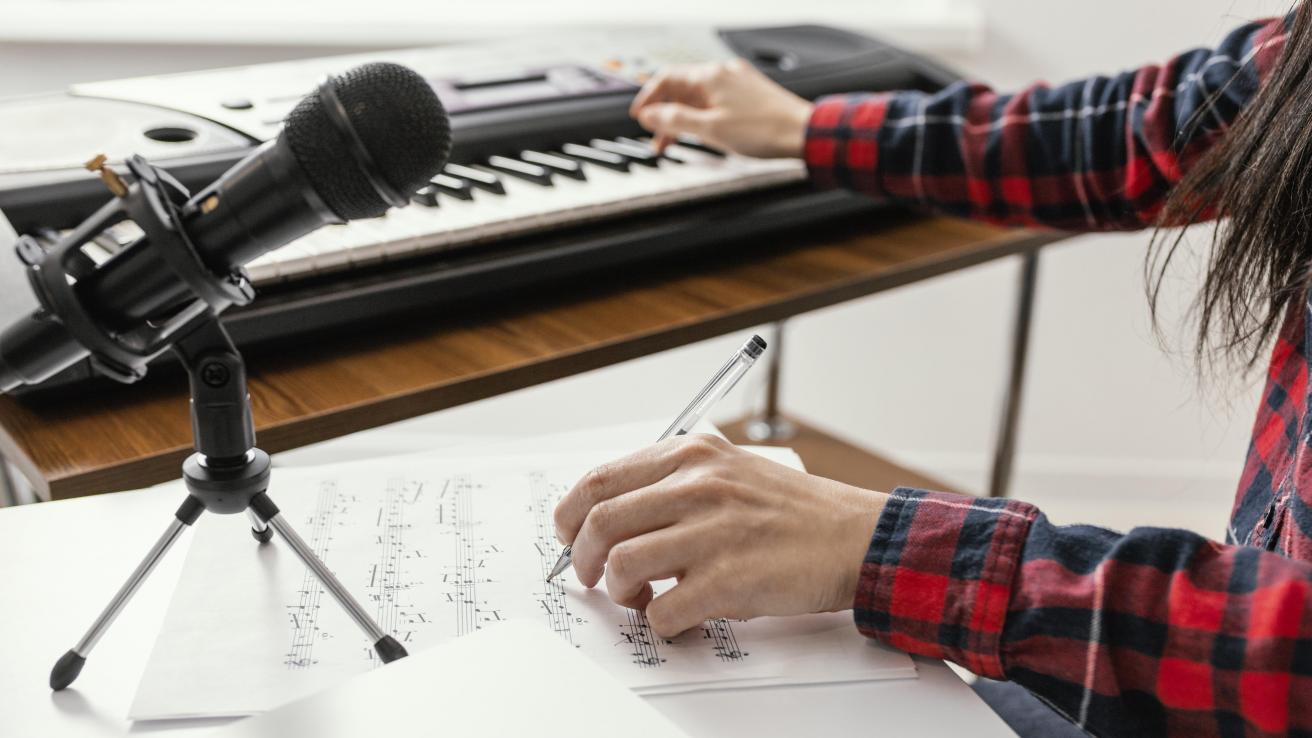primer plano de las manos de una persona tocando un teclado y un microfono