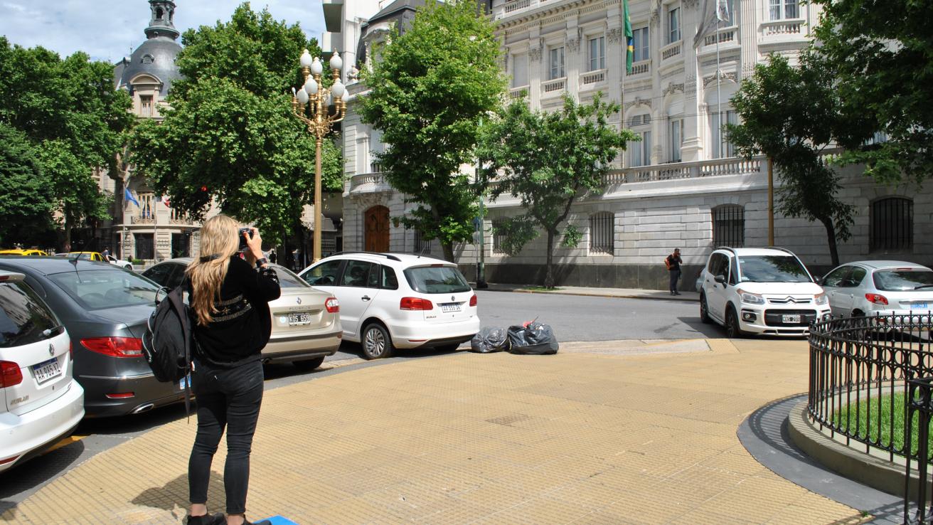 Mujer sacando foto en la calle a un edificio 