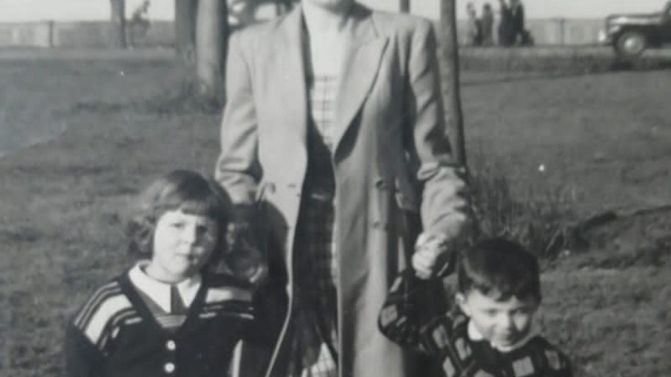 Una mujer toma de la mano a dos niños. Foto en blanco y negro