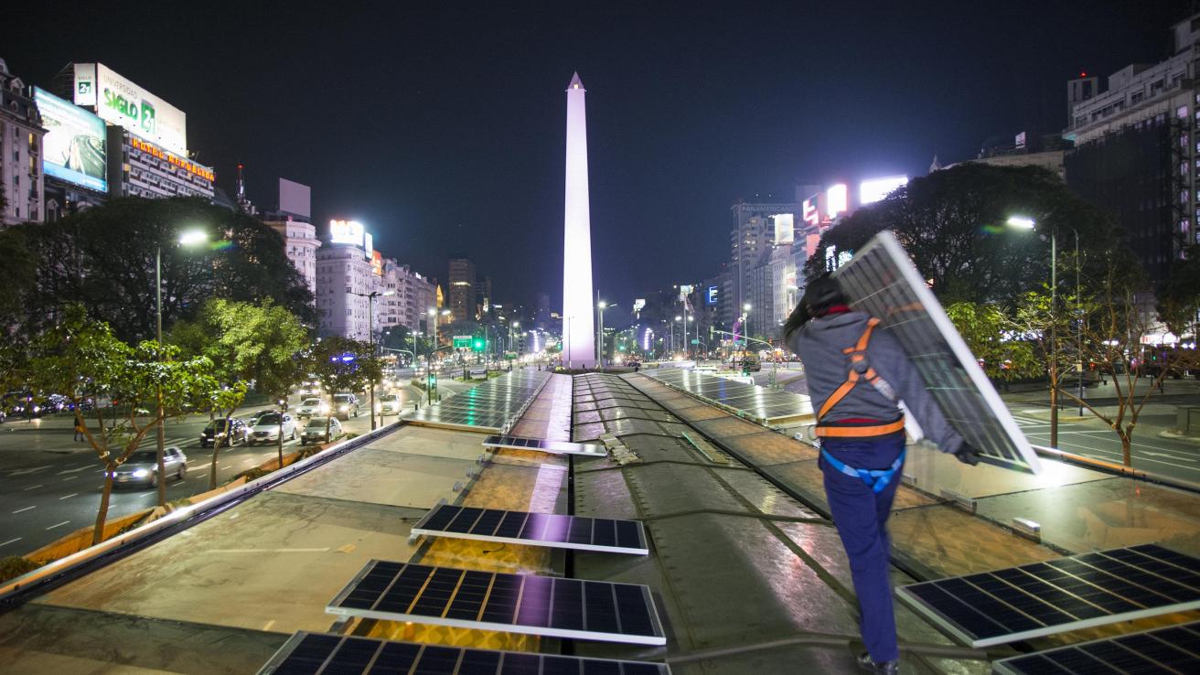persona con un panel solar en la ciudad de buenos aires de noche