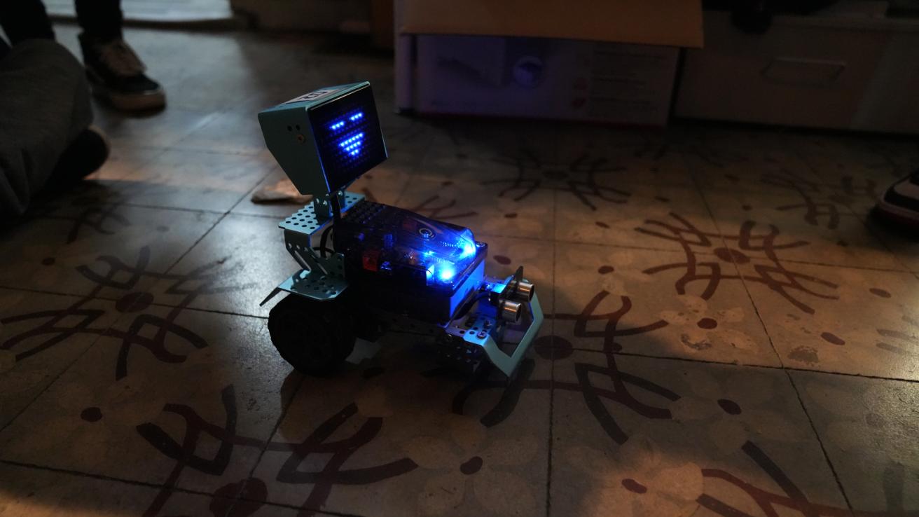 Mini robot azul, con luces azules apoyado en el piso