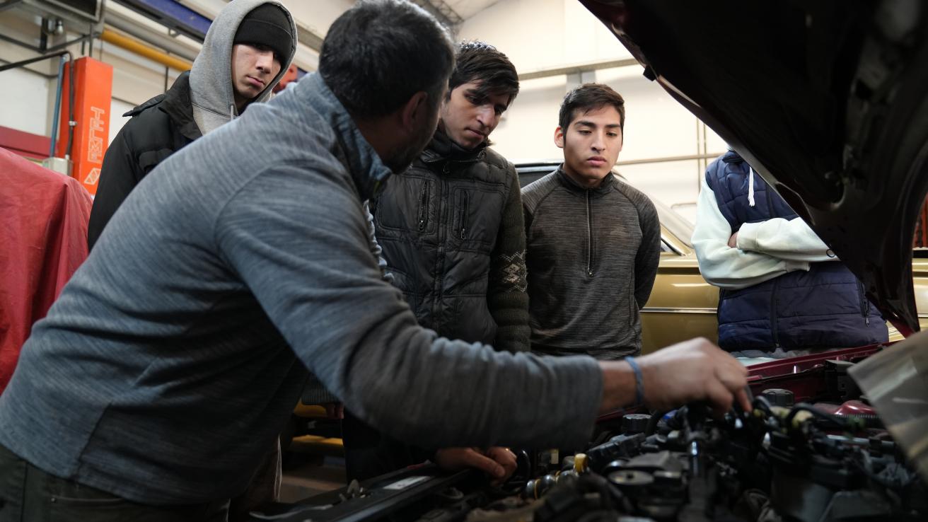 Gurpo de personas mirando el motor de un auto