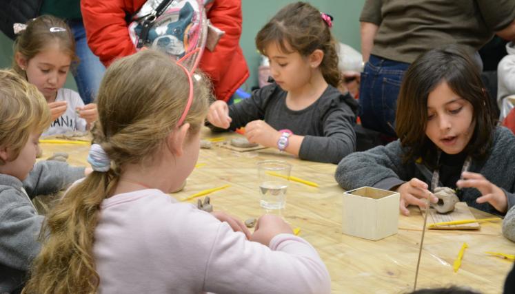grupo de niños y niñas sentados en una mesa experimentando la cerámica