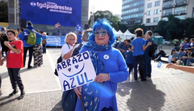 Fotografia de mujer con peluca azul y cartel en mano que dice "Abrazo azul"