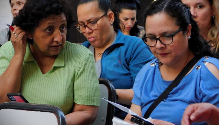 Imagen en la que destacan 3 mujeres dos de ellas hablan sobre el contenido del material brindado