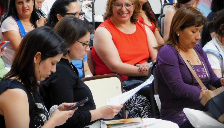 Imagen tomada en lateral de una parte del grupo presente. En su mayria mujeres sentdas leyendo el contenido del kit de regalo