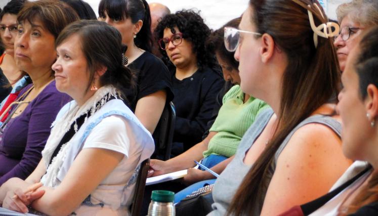 Foto tomada en lateral en que se observa a las personas, en su mayoria mujeres, concentradas escuchando al orador