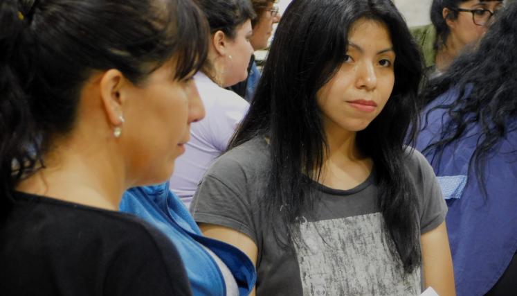 Fotografia tomada a un grupo de trabajo en la que destacan dos mujeres. Un de ellas esta de perfil y otra de frente mirando con atencion a otra persona que no se ve y está hablando