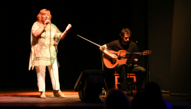Mujer cantando y hombre tocando la guitarra en escenario