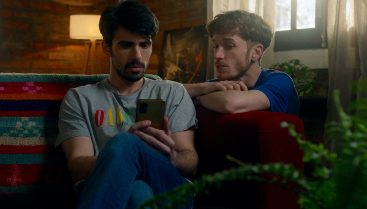 Dos hombre sentados mirando un celular