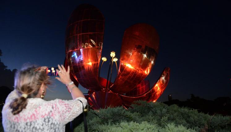 Señora sacando foto de la Floralis iluminada de noche