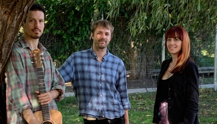 Tres personas en un parque, una de ellas con una guitarra