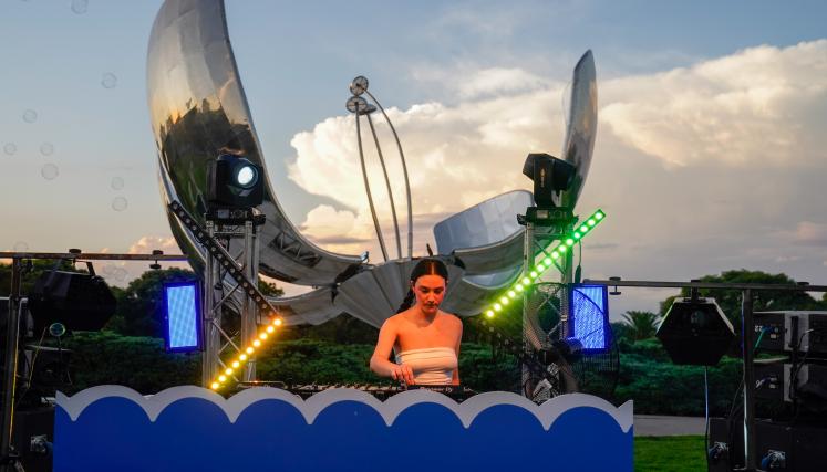 Mujer DJ pasando música adelante de la Floralis